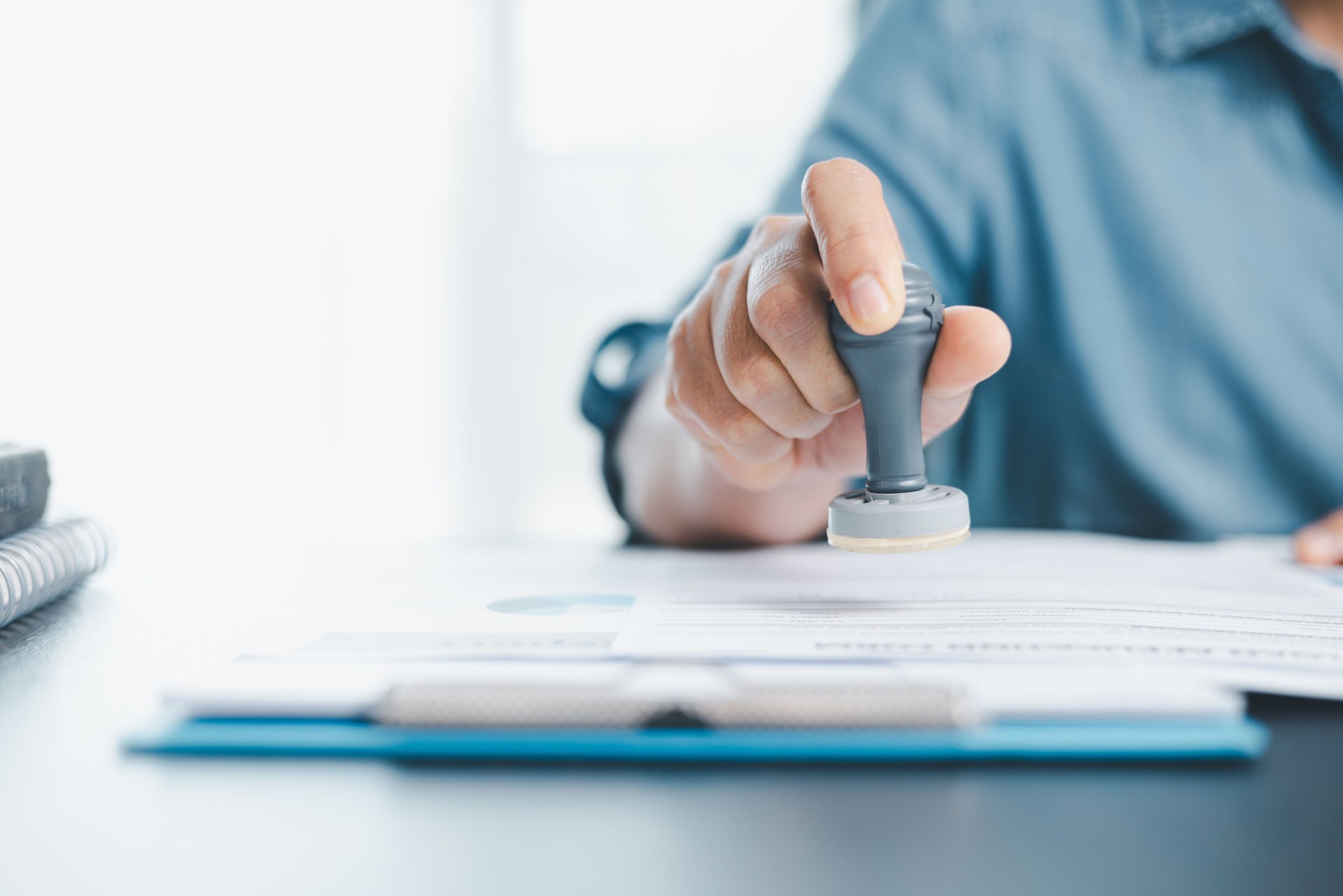 Businessman hands stamp approve on financial business approval document paper. Man hand accepted permit contract agreement. Broker manager sign contract bank guarantee approved stamp application form